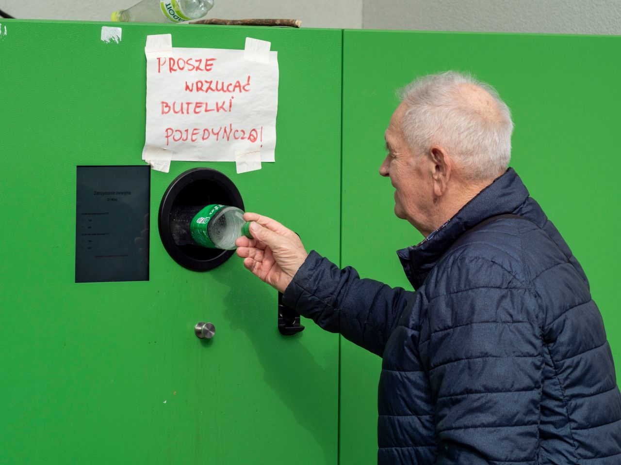 Senior man using a bottle return machine in Wrocław, Poland.